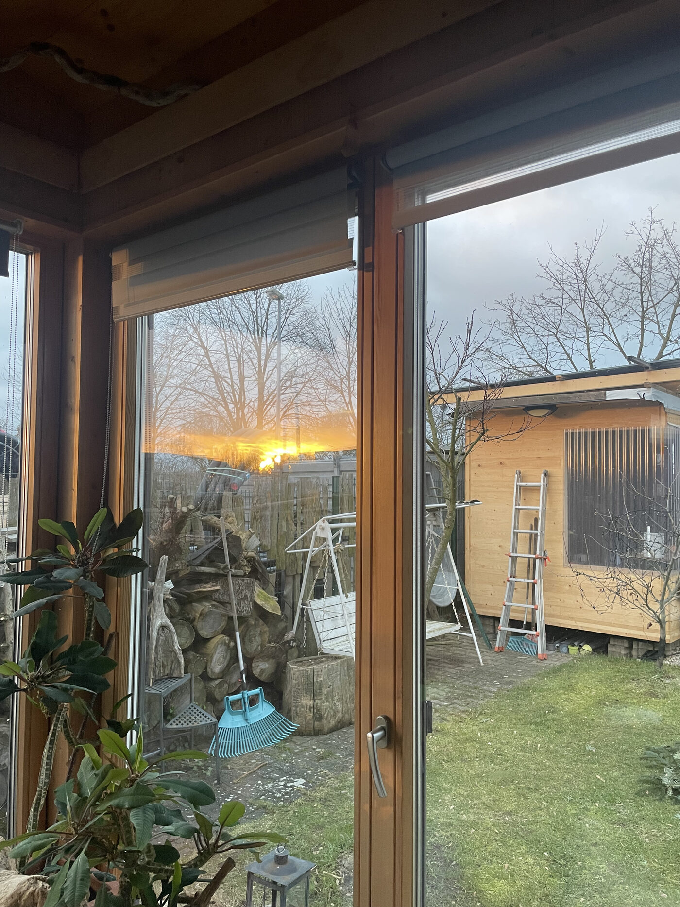 Bodentiefe Glasfront mit Blick in den Garten bei Sonnenuntergang